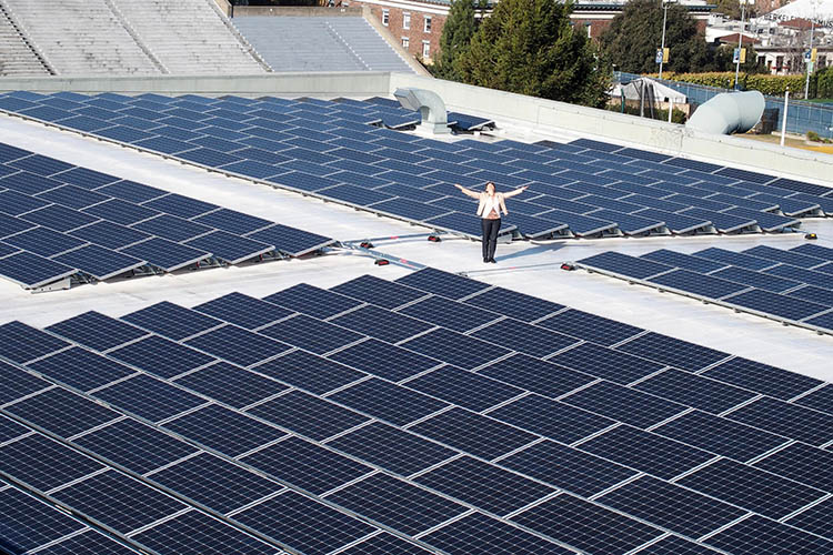 a woman stands with open arms near solar panels