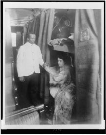 A Pullman porter hands a woman a glass of water