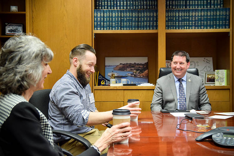 three people sit at a conference table