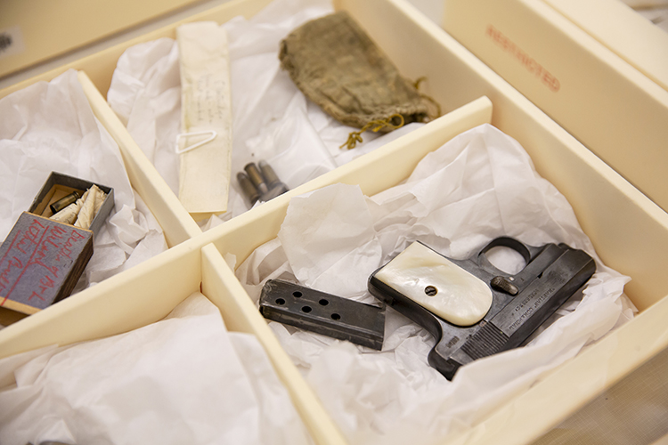 a box of crime scene evidence, including a gun and bullets