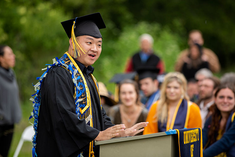 Pheng Lor stands outside at a podium at Alternative graduation