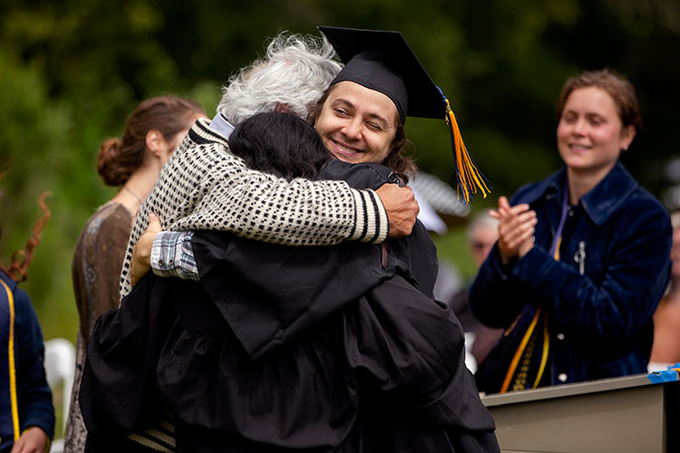 Two students hug Ignacio Chapela during the Alternative graduation ceremony