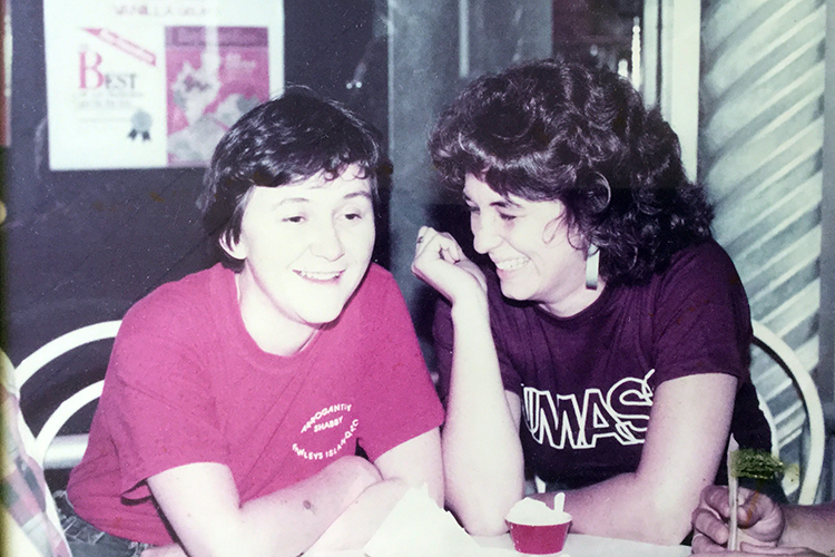 Esther and Martha sitting at a table laughing in the 1980s
