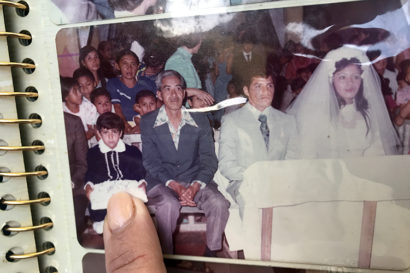 Teresa and her husband José during their wedding with a bunch of people sitting behind them