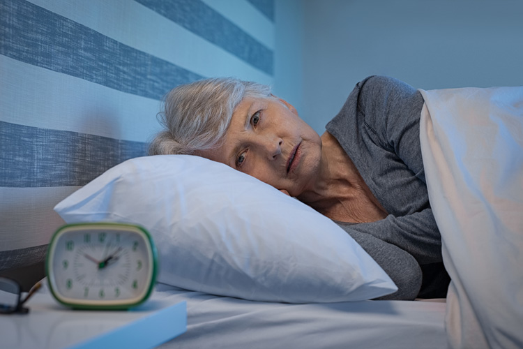 woman awake, staring at clock