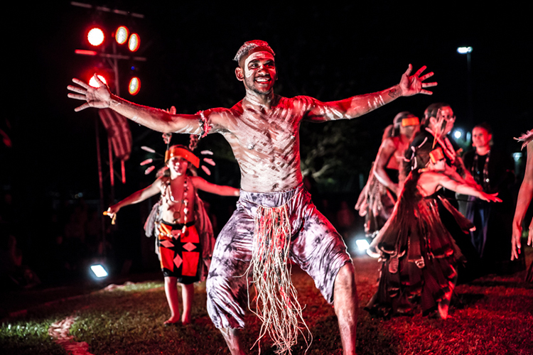 Young male dancer wearing body paint smiling with his arms outstretched