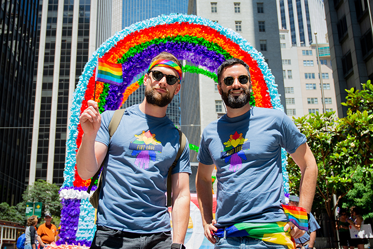 two men at pride parade pose and smile