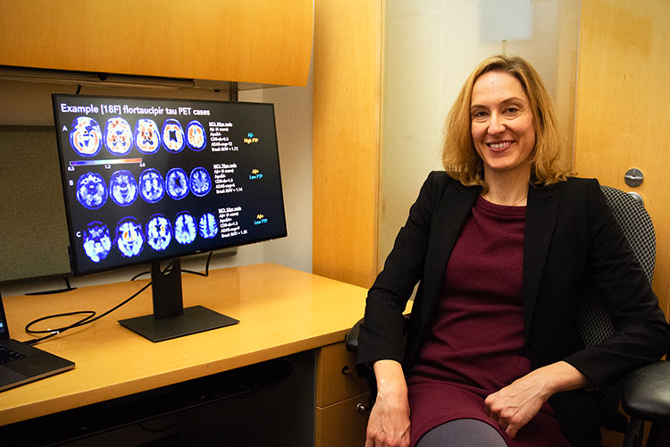 A photo of Susan Landau next to a computer that shows PET brain scan images