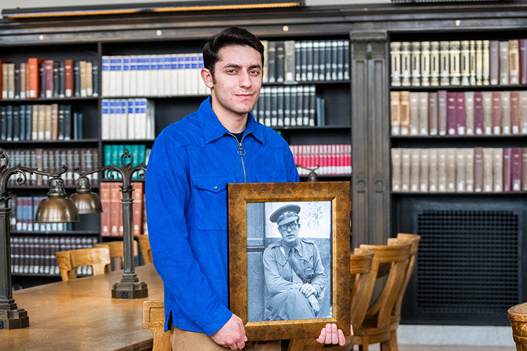 Student Milton Zerman holds a framed photo of Robert Merriman, a PhD student who left campus in the late 1930s to fight in Spain.