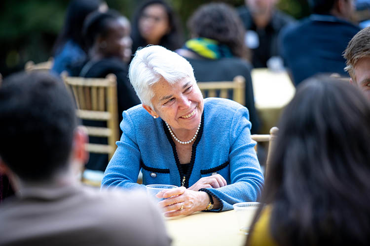 Carol Christ sits at a table and talks with students