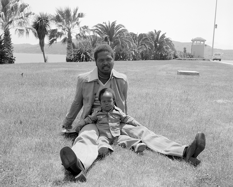 man and his toddler sitting on the grass