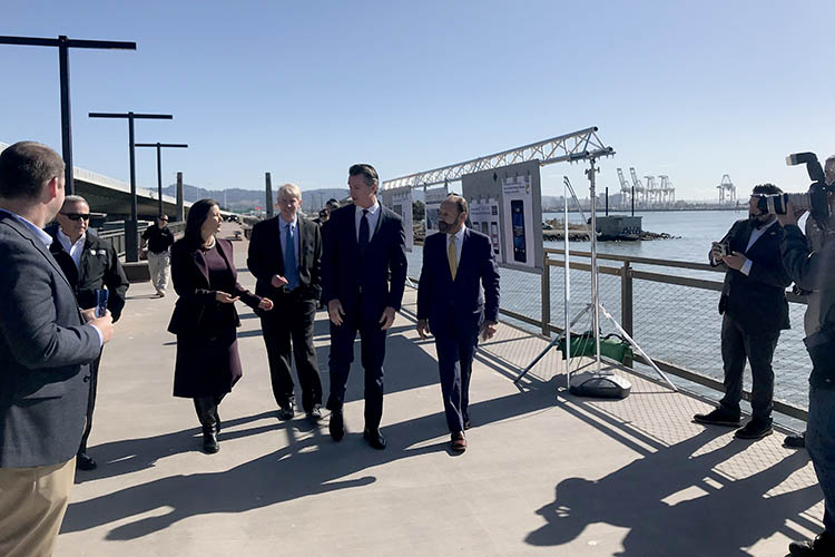 the four people named in the caption walk together near the water in oakland