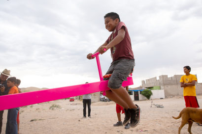 Boy smiles as he rides a teeter totter on the border wall