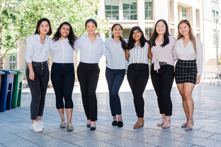 seven women stand with linked arms outside of the Haas School of Business