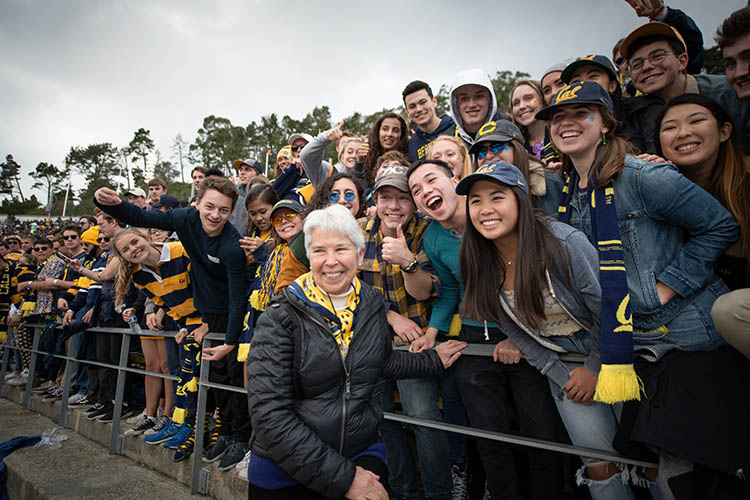 Chris stands with students in the stands of memorial stadium