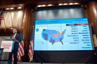 Man standing in front of screen with a picture of the United States map on it.