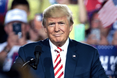 U.S. President Donald Trump, in a blue suit and red and white tie, speaks at a campaign event.