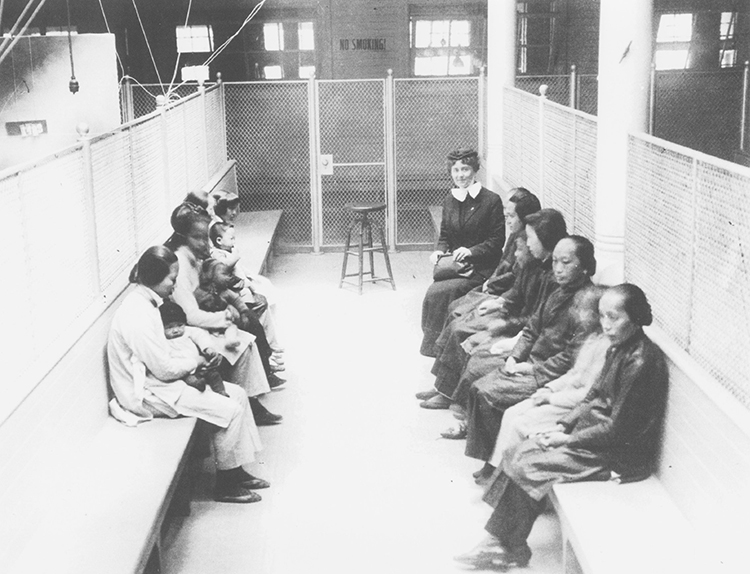 A group of women sitting on benches in a caged area.