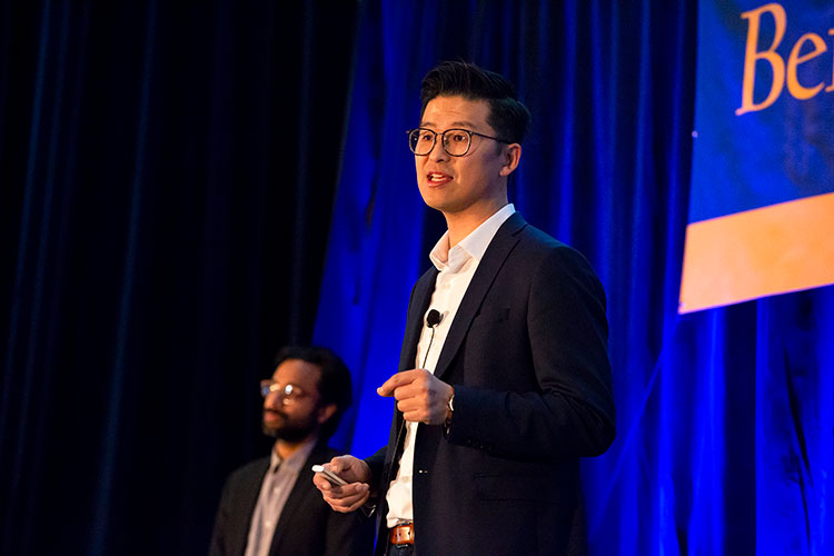 Man standing on stage speaking.