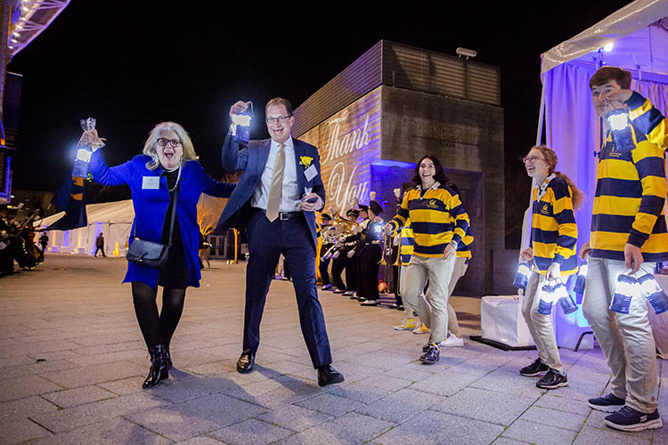 Eric Stern and Rachel Stern smile as they hold lanterns while students cheer them