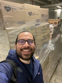 Ruben Canedo smiling in front of boxes of food