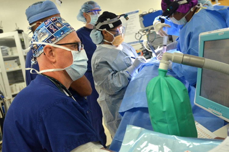 Doctors and nurses wearing masks gather in an operating room