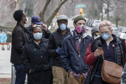 voters wearing masks lined up outside a polling place