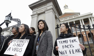 Women from the Asian American Commissions hold protest signs against anti-Asian racism