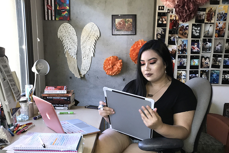 Resident adviser Janey Lopez sits at a desk in her dorm room