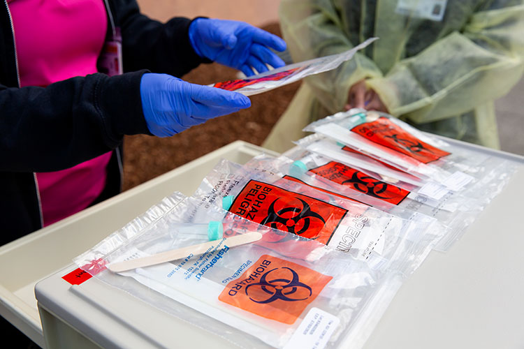 A photo of a pair of gloves hands holding biohazard bags