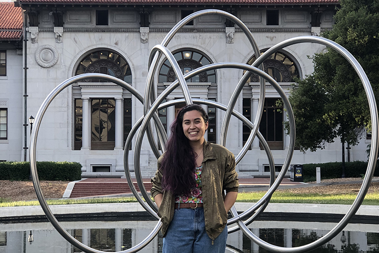 Micaela Camozzi poses in front of a sculpture by the miner's building on Berkeley's campus