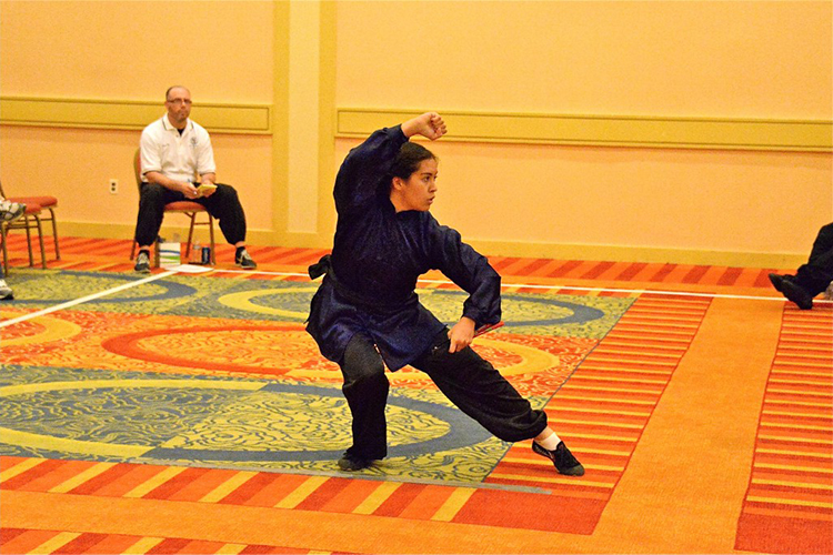 Micaela Camozzi poses in a martial arts stance while wearing a Kung Fu uniform