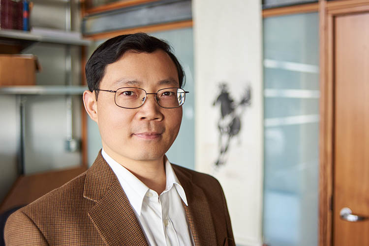 Junqiao Wu looks at the camera while standing in his lab