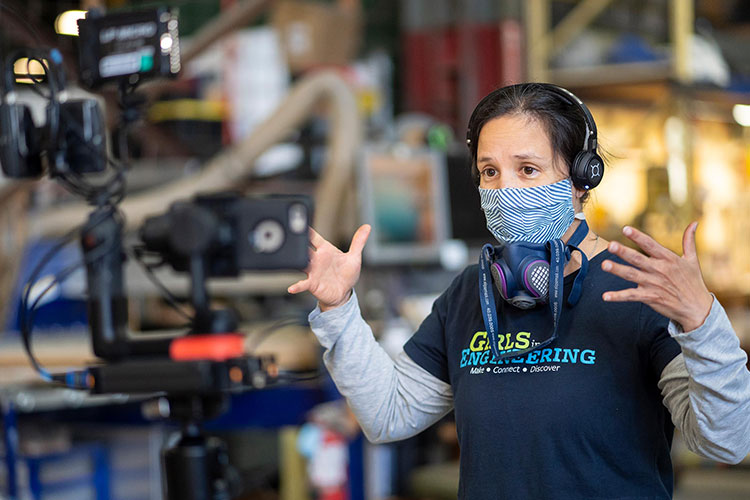 A women wearing a cloth face mask and a blue tee shirt that says 