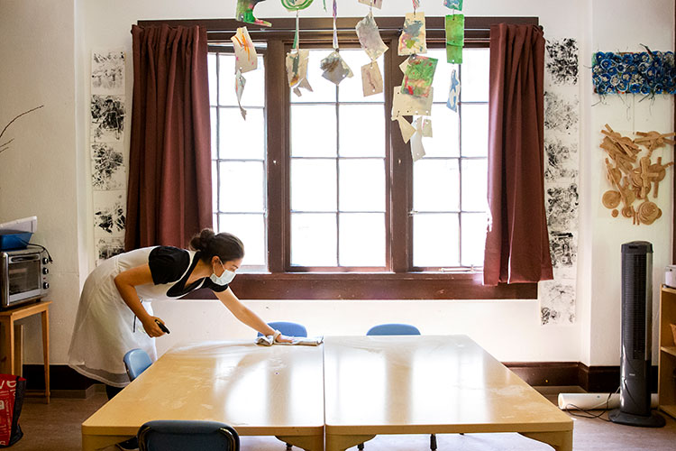 A staff member at Rockridge Little School in Oakland, California, uses a quiet moment to disinfect tables used by preschool students.