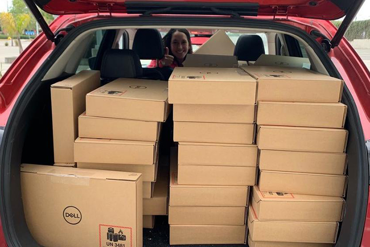 Jennifer McNulty, the analyst for the Student Technology Fund, looks over the top of many boxes of laptops in the back of a car that are being readied to give to Berkeley students in need.