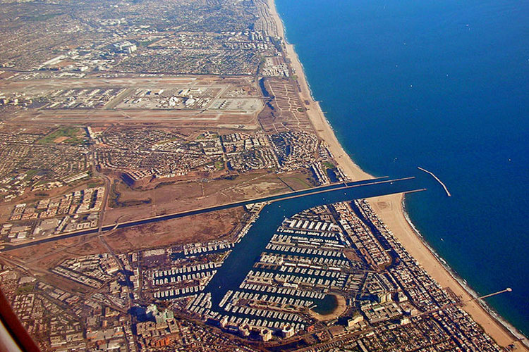 An aerial photo of a coastline showing a bright blue ocean and a developed urban area