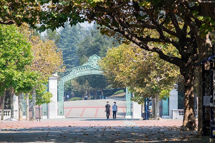 Two students walk toward Sather Gate on a virtually empty campus during the coronavirus pandemic.