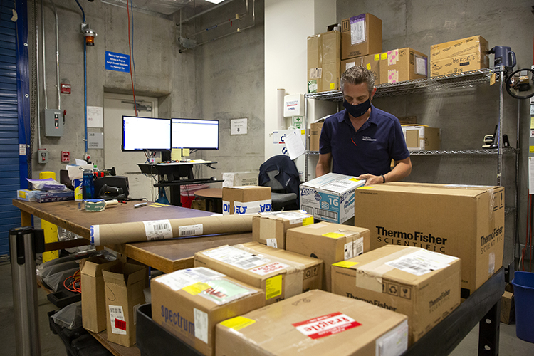 A shipping and receiving coordinator at the College of Engineering is getting overwhelmed with the volume of mail he has to handle during the pandemic. He is surrounded by boxes that need to be delivered.