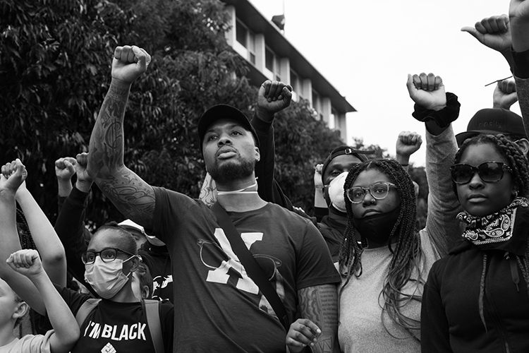 Protestors holding their fists up include NBA star Damien Lillard