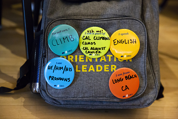 A backpack for a Golden Bear Orientation student leader is covered with colorful homemade buttons that indicate the leader's major, hometown and other fun facts, including his gender pronouns