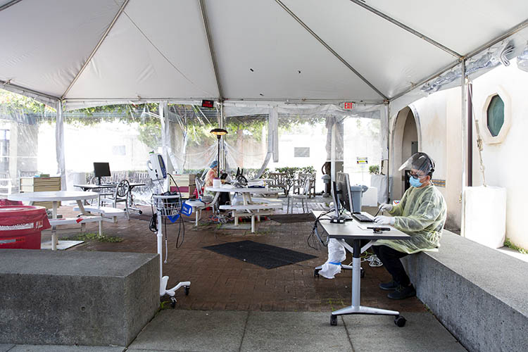 inside a testing tent outside the tang center. healthcare workers sit in front of computers and medical equipment