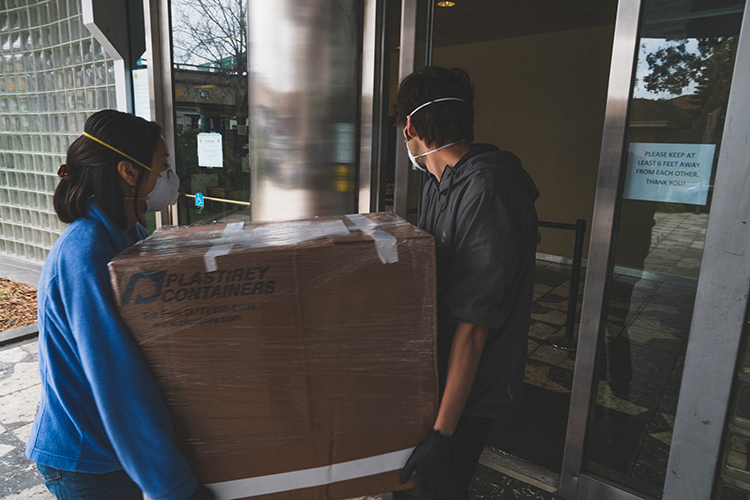 In masks, Abrar Abidi and Yvonne Hao from UC Berkeley deliver a large box 