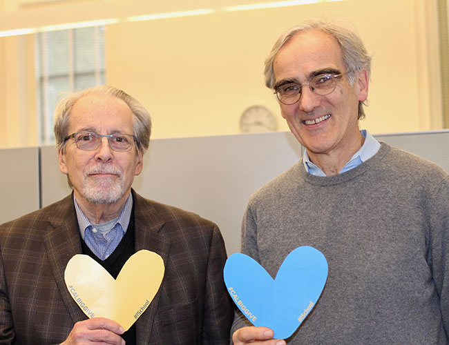 Geoffrey Nunberg stands beside his friend Paul Nunberg. Both hold paper hearts.