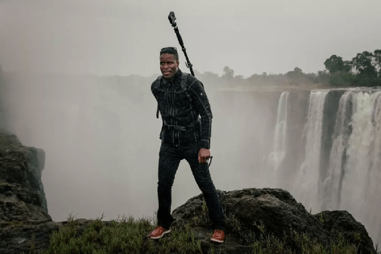 Student standing with camera equipment at Victoria falls in Zimbabwe