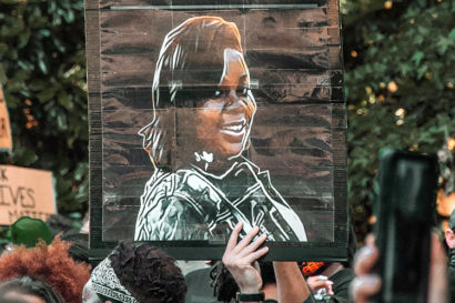 a protestor holds a sign with a drawing of Breonna Taylor