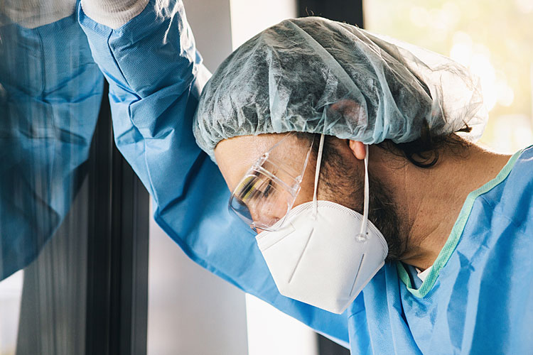 Health worker with mask looking exhausted.