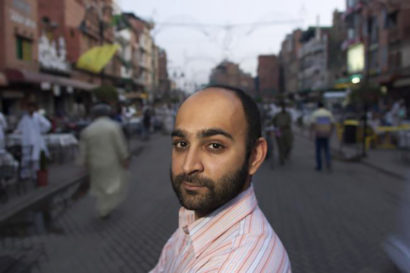 Mohsin Hamid stands in a busy street, looking at the camera
