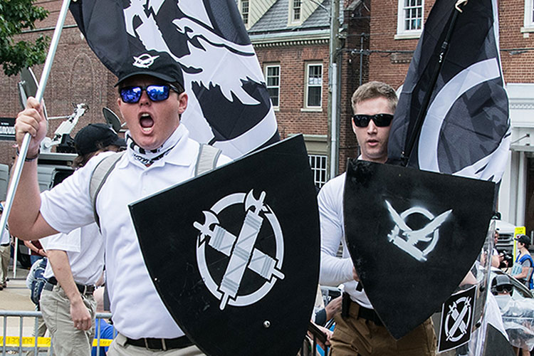 Two white nationalist protesters with flags and shields at the "Unite the Right" rally in Charlottesville, Va., in 2017.