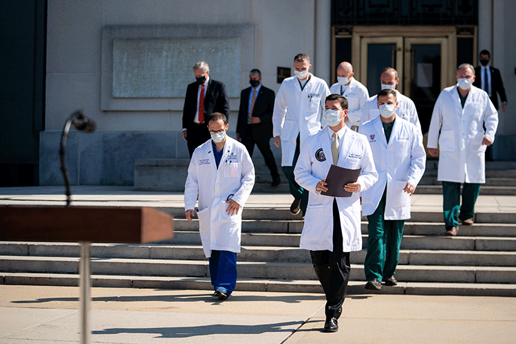 A photo of a group of doctors in white coats walking down a set of stairs outside.